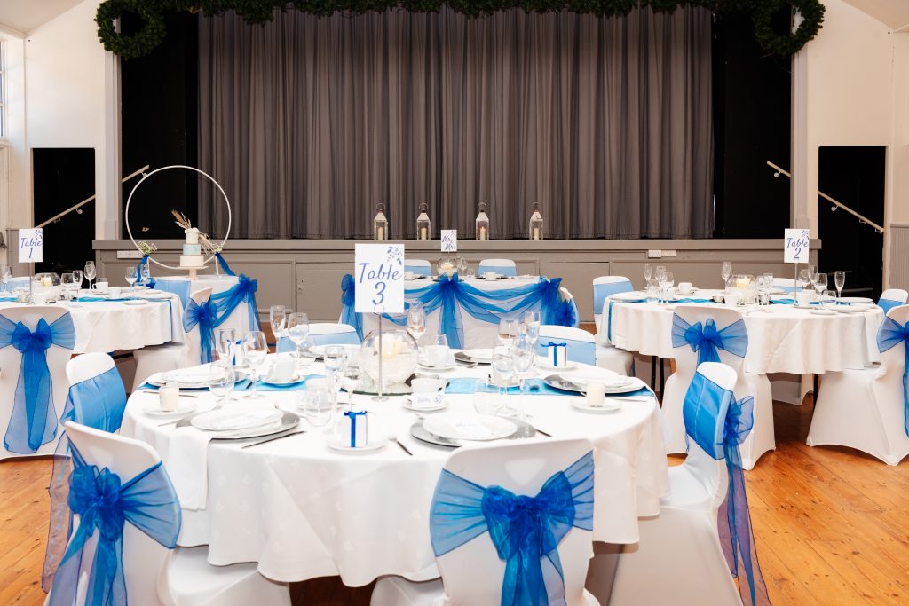 Circular tables set up with white and blue coverings.